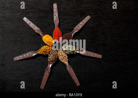 spices in spoons on black background Stock Photo