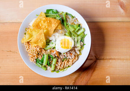 Tom yum noodles special put a small line, instant noodles, convolvulus, boiled egg and dumpling in a bowl of white paste on wood chamcha, on top view Stock Photo