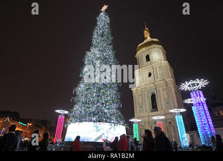 People seen next to the main Christmas tree of Ukraine, on the St. Sophia Square in Kiev, Ukraine. The main Christmas tree of Ukraine, was decorated in the northern lights style, it topped the rating of the most beautiful Christmas trees in Europe, according to the European Best Destinations website. The list included Christmas trees of 16 European. Stock Photo