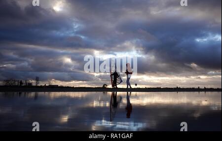 Berlin, Germany. 30th Dec, 2018. The sky is reflected in a puddle of rain in front of a wind skater and a walker on the Tempelhof field. Credit: Kay Nietfeld/dpa/Alamy Live News Stock Photo