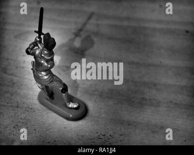 Black and White Image of Knight Wielding Sword on Wooden Table Stock Photo