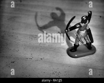 Black and White Image of Knight Wielding Bow on Wooden Table Stock Photo