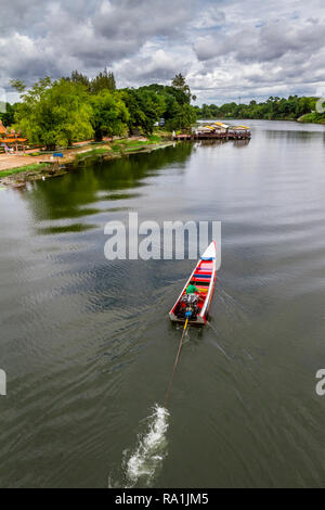 Longtail boat from above running along the kwai river and next to a Buddhist temple on the left. Stock Photo