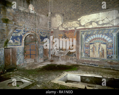 Italy. Herculaneum. Ancient Roman city destroyed by the eruption of the Vesuvius in 79 AD. Atrium of the House of Neptune and Amphitrite. 1st century. Nympheum with central niches, decorated with geometric and floral motifs and mosaics of hunting scenes with dogs and deer. On the back wall, the mosaic of Neptune and Amphitrite. Campania. Stock Photo