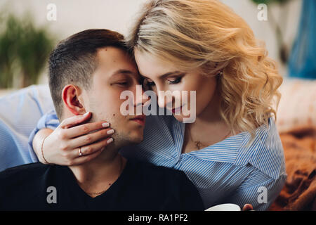 Beautiful blonde girlfriend with handsome boyfriend touching face by face. Stock Photo