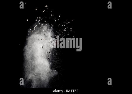 Launched white powder white small stones splash on black background. Bizarre forms of of white powder with small stones explosion cloud against dark b Stock Photo