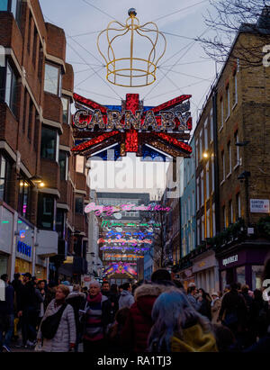 Shoppers on  Carnaby Street, Soho, London under Christmas Neon Light Installation. December 2018 Stock Photo