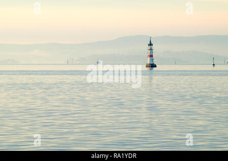 Small white lighthouse isolated on pink sky background at sunset, in entrance to Oslo harbour. Winter time and calm sea in inner Oslofjord waters. Stock Photo