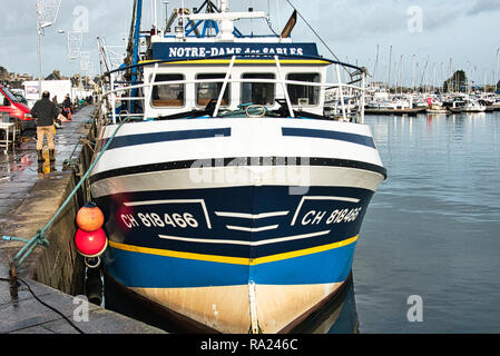 St Vaast, Normandy, France -December circa, 2018. Fishing scallops seafood boat in the harbour with fish net, with soft warm light at end of afternoon Stock Photo