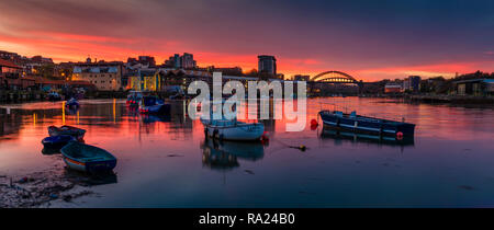 River Wear Fish Quay towards the iconic Wearmouth bridge, fishing boats in foreground, sunset producing a stunning array of colours & reflections Stock Photo