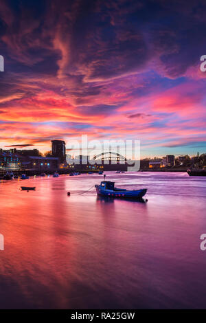 River Wear Fish Quay towards the iconic Wearmouth bridge, fishing boats in foreground, sunset producing a stunning array of colours & reflections Stock Photo