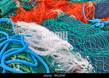 Close up view of colored ropes and nylon nets used to fish. Abstract image of maritime equipment in a port. Detail of pattern of colorful fishnets. Stock Photo