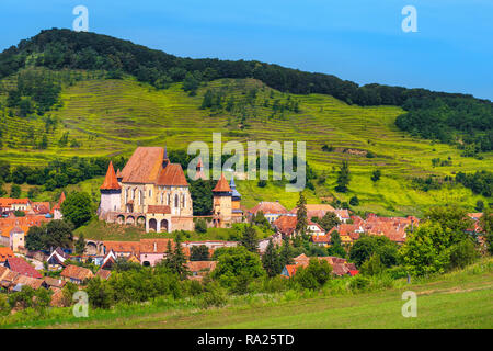 Beautiful travel destination, agricultural area and famous saxon fortified church with Transylvanian village in background, Biertan, Transylvania, Rom Stock Photo