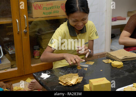 gold beating, young woman cutting and packing leaf gold in bamboo paper Stock Photo