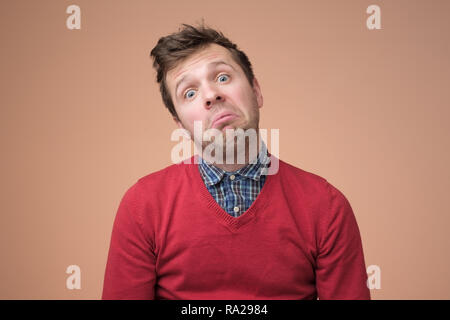Very bored adult man in red sweater looking tired and sick, over brown background Stock Photo