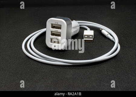Three port USB car cigarette adapter and cable on a dark grey background Stock Photo