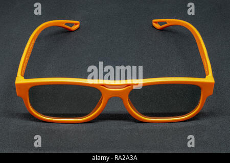 Orange 3 Dimensional glasses on a dark grey background Stock Photo