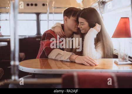 Loving young couple in winter time sitting in a cafe Stock Photo