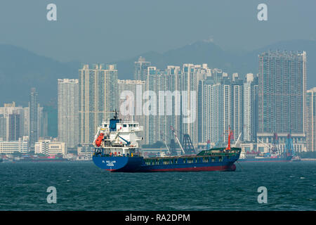 The Panamanian flagged general cargo vessel 'PL Hau Laam' moored off Tai Kok Tsui in Hong Kong with towering apartment blocks fringing the harbour. Stock Photo