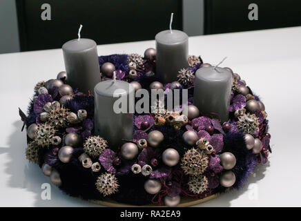 Purple advent wreath with baubles and four grey candles on a white table Stock Photo