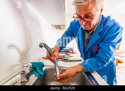 Professional handyman is fixing the kitchen tap with his tools Stock Photo