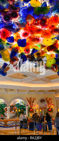 Ceiling designed with Dale Chihuly colorful glass sculpture of thousdands of glass flowers overhead of the hotel guests in the lobby's reception area  Stock Photo