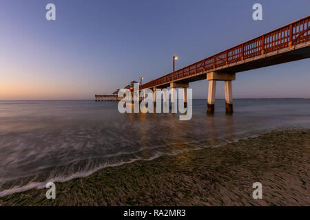 Beautiful view of a wooden Pier on the Atlantic Ocean during a vibrant sunrise. Taken in Fort Myers Beach, Florida, United States. Stock Photo