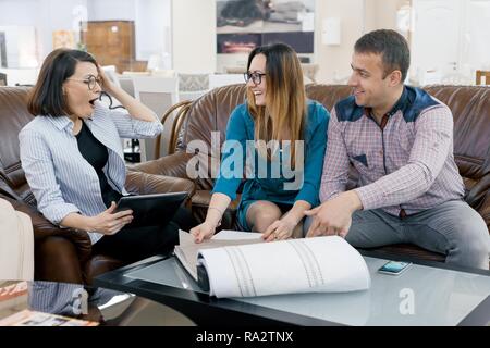 Woman designer curtain working with clients young family choosing fabrics to their new home. Stock Photo