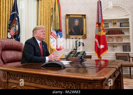 U.S. President Donald Trump participates in a Christmas Day video teleconference with military service members from the Oval Office of the White House December 25, 2018 in Washington, DC. Trump broke with tradition and used the call to advance his case for a border wall, his isolationist foreign policy views and his insistence that his campaign did not collude with Russia instead of the usual holiday message delivered by past presidents. Stock Photo