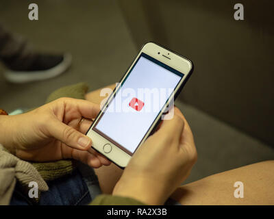 Woman opening YouTube mobile app with logo on iPhone screen while commuting on subway train Stock Photo