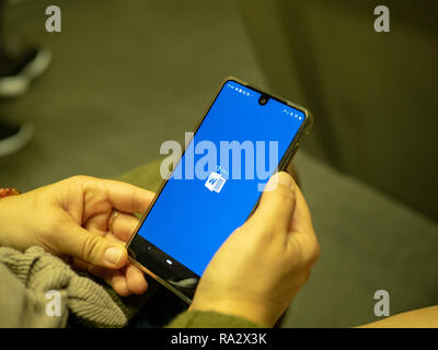 Woman opening Microsoft Office 365 Word app with logo on Android screen while commuting on subway train Stock Photo