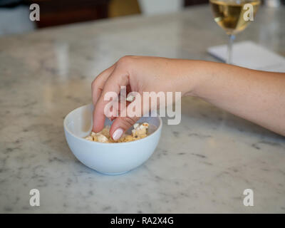 Woman manicured hand inside a small bowl of popcorn with wine Stock Photo