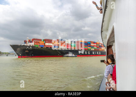 Panama Canal, Panama - Mar 15th 2018 - A huge ship of Yang Ming brand navigating through the Panama Canal seen from a small touristic boat in Panama Stock Photo