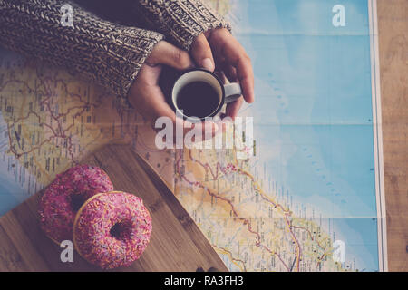 Above top view of mornig time with pair of woman hands taking a cup of black italian coffee looking and using a paper map for next travel - two pink d Stock Photo