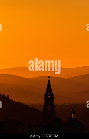 Church tower in the sunset silhouette with mountains in the background Stock Photo