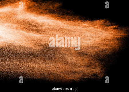 Orange powder dust particles explosion on black  background. Stock Photo