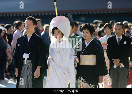 Shinto wedding procession with bride wearing the traditional watabōshi white hood walking with groom in the Meiji Jingu Shinto Shrine Stock Photo