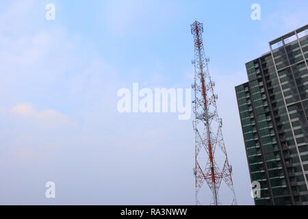 high antenna tower in city with blue sky in background Stock Photo