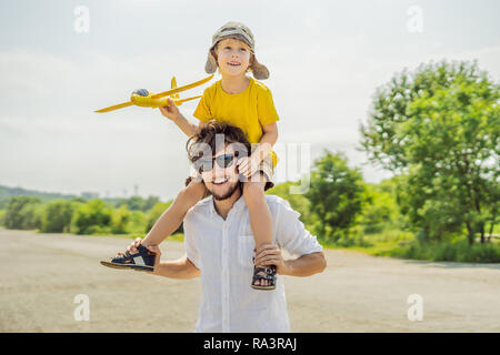 Happy father and son playing with toy airplane against old runway background. Traveling with kids concept Stock Photo