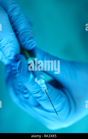 Physician injector arms in sterile uniform holding syringe Stock Photo