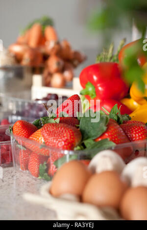 Fresh ingredients of vegetables being prepped in a kitchen with strawberries, peppers and eggs Stock Photo