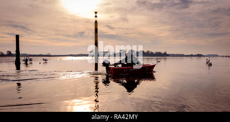 A boatman in his dinghy at low tide at Bosham Harbour near Chichester, West Sussex UK. Stock Photo