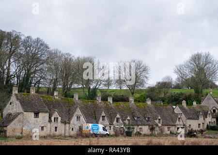 A Thames Water vehicle drives past picturesque cottages at Arlington Row in the Cotswolds village of Bilbury, UK. December 2018. Stock Photo