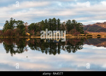 Pine trees and buildings reflected in the still waters of Loch Sheil, Argyll and Bute, Scotland. 23 December 2018 Stock Photo
