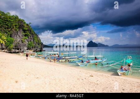 Outrigger boats before a storm anchoring on a sandy beach in the Bacuit archipelago, Palawan, Philippines Stock Photo