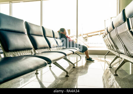 Asian woman sleeping on bench in airport terminal Stock Photo