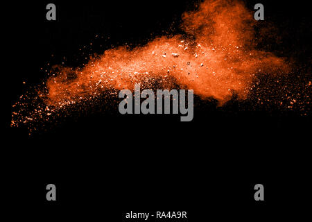Orange powder dust particles explosion on black  background. Stock Photo