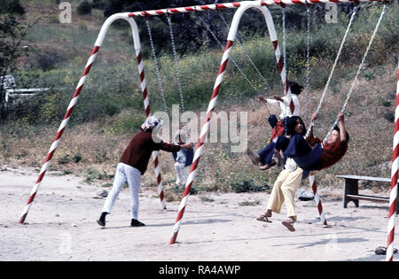 1975 - Children play on a swing at a temporary housing facility for Vietnamese refugees. Stock Photo