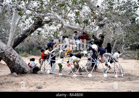 1975 - Children play on a piece of playground equipment at a temporary housing facility for Vietnamese refugees. Stock Photo