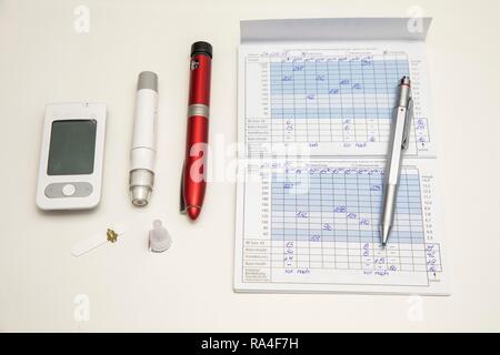 Diabetes, left blood glucose meter, test strip, lancing device, insulin pen, blood glucose diary, Germany Stock Photo